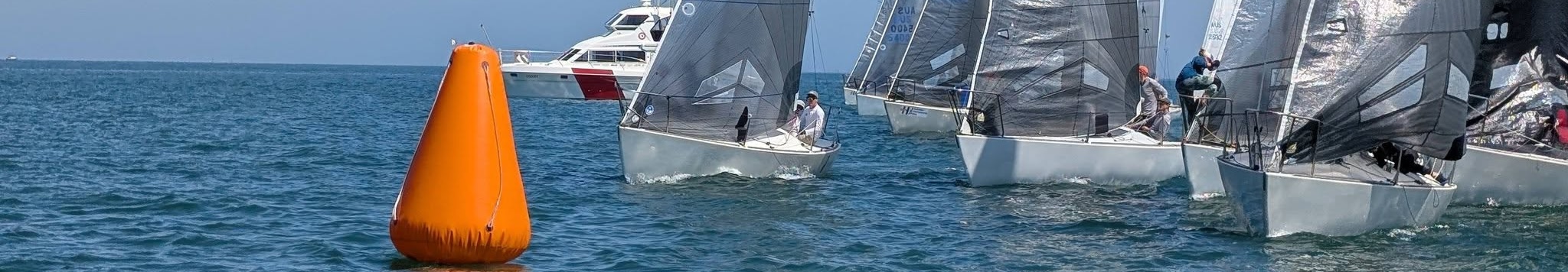 Racing boats approaching an orange start mark on open water
